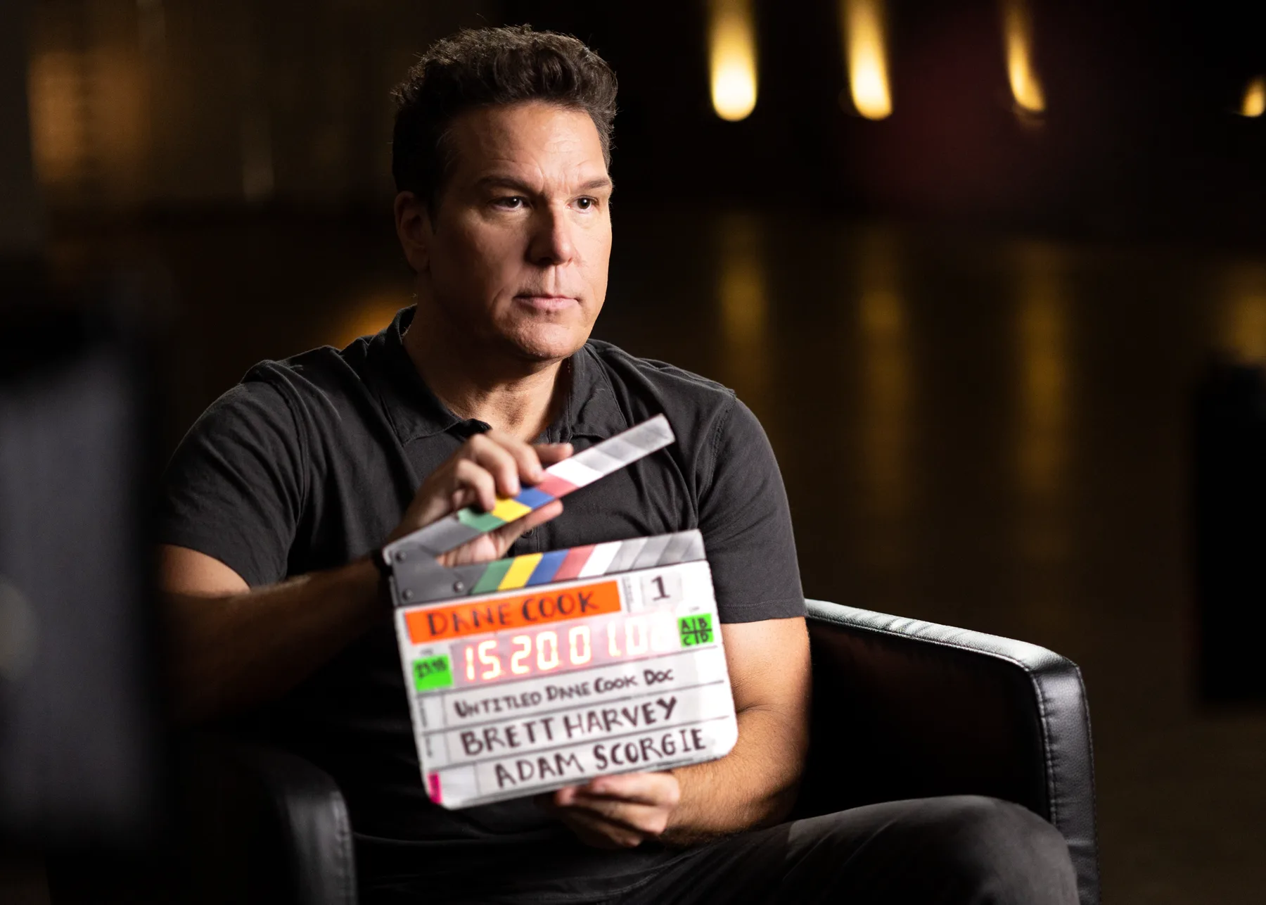 Dane Cook holding a production slate during an interview